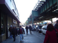 La conocida Avenida Roosevelt, el centro comercial y cultural de Corona, New York. En el fondo la elevada línea numero 7 del metro de Nueva York sigue paralelo a Roosevelt mientras se escucha al español en las calles abajo.
